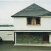 A curved stone wall at ground level leads to the main entrance